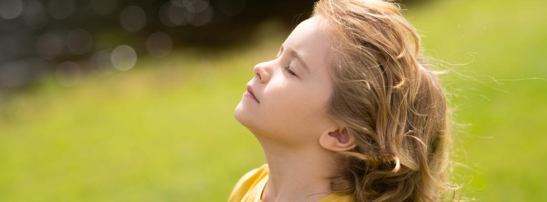 Kind atmet frische Luft. Kinderglauben, Lob und Glück und Freiheit. Kinderruhe im Sommerpark. Kid legte Gesicht zur Sonne, schloss ihre Augen und füttert Energie der Natur, Träume.
