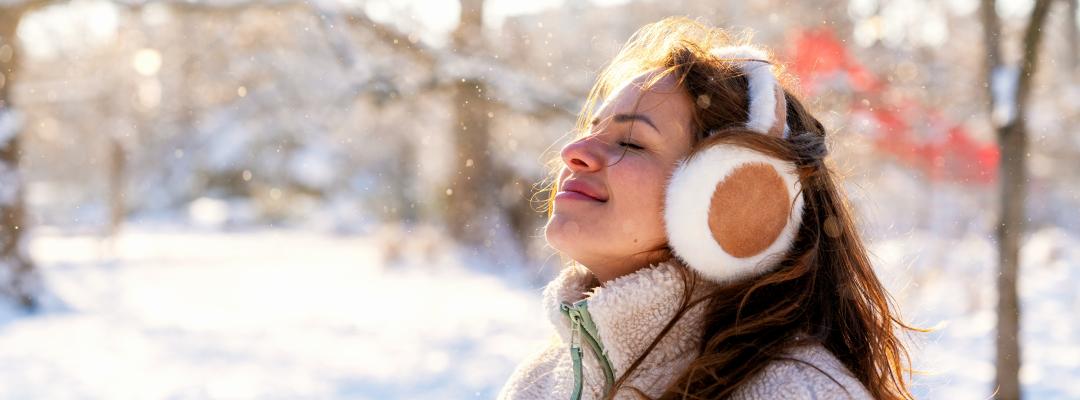 Eine Frau, die im Schneepark frische Winterluft schnuppert