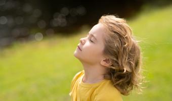 Kind atmet frische Luft. Kinderglauben, Lob und Glück und Freiheit. Kinderruhe im Sommerpark. Kid legte Gesicht zur Sonne, schloss ihre Augen und füttert Energie der Natur, Träume.