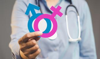 Nahaufnahme eines Arztes in einem blauen Hemd mit rosa und blauen Geschlechtersymbolen, die Gesundheitsbewusstsein, Geschlechtsidentität, Gleichberechtigung und Betreuung in medizinischen und Wellness-Umgebungen repräsentieren.