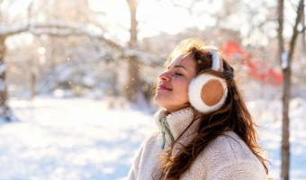 Eine Frau, die im Schneepark frische Winterluft schnuppert
