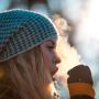 Woman breathing on her hands to keep them warm at cold winter day