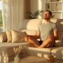 Mann zu Hause meditieren tun Yoga Übungen sitzen auf einer Couch und atmen frische Luft bei Sonnenuntergang